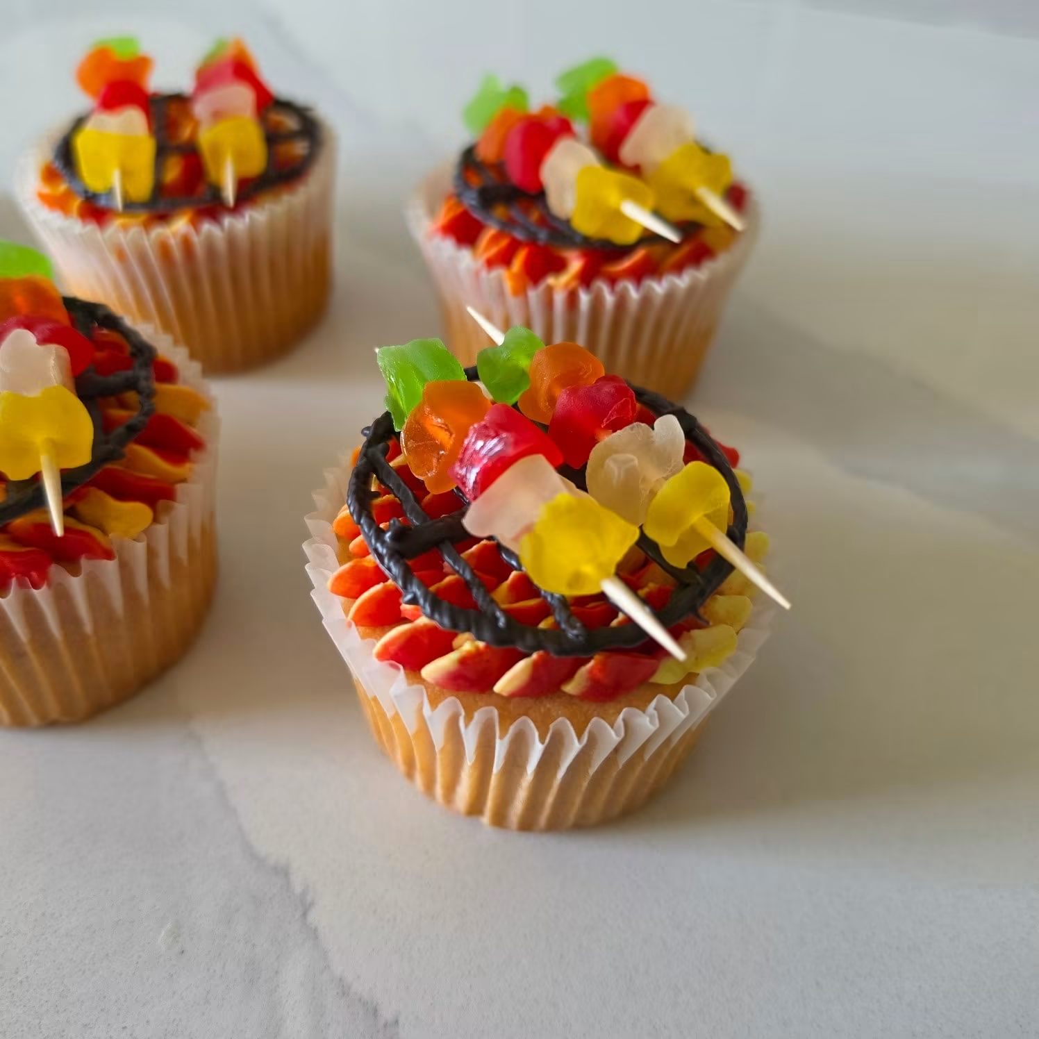 Cupcakes decorated to look like little BBQ grills with gummy kebab skewers